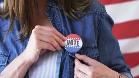 Middle-aged-Caucasian-woman-pins-a-'VOTE'-badge-on-her-denim-jacket
