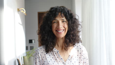 Portrait-of-happy-biracial-woman-with-curly-hair-at-home,-slow-motion