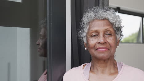 Portrait-of-happy-senior-african-american-woman-smiling-by-window,-copy-space,-slow-motion