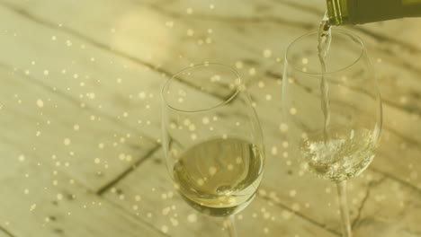 Composite-of-white-wine-being-poured-into-glasses-over-wooden-background