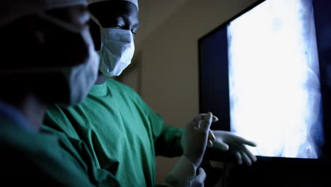Diversos-Cirujanos-Discutiendo-Con-Exploraciones-De-Rayos-X-En-El-Quirófano-Del-Hospital,-Cámara-Lenta