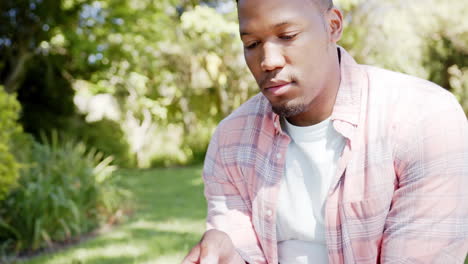 Glücklicher-Afroamerikanischer-Mann,-Der-Zu-Hause-Im-Garten-Sein-Smartphone-Benutzt,-Zeitlupe