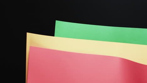Video-of-red,-yellow-and-green-papers-with-copy-space-on-black-background