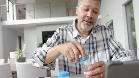 Älterer-Mann-Mit-Gemischter-Abstammung-Und-Medikamenten-Führt-Videoanruf-Mit-Arzt-Auf-Tablet,-Zeitlupe