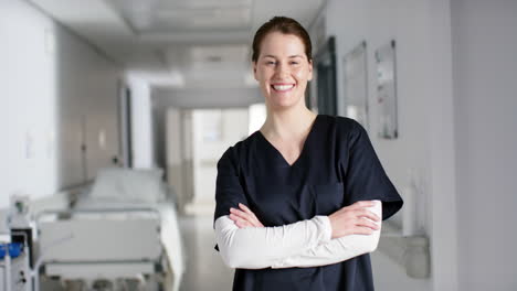Portrait-of-happy-caucasian-female-doctor-wearing-scrubs-in-hospital,-slow-motion
