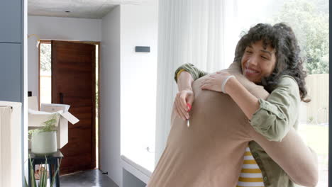 Happy-biracial-couple-embracing-with-cartons-at-new-house,-slow-motion