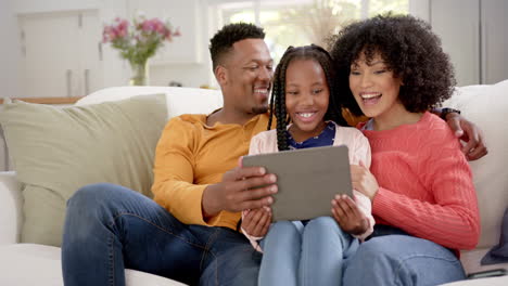 Felices-Padres-Afroamericanos-Con-Su-Hija-Usando-Tableta-En-Casa,-Cámara-Lenta