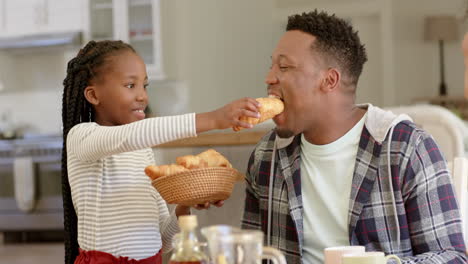 Happy-african-american-father-and-daughter-having-breakfast-at-home,-slow-motion