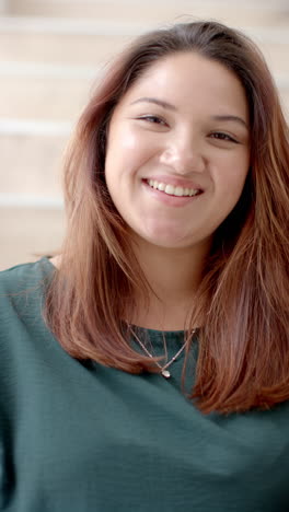 Vertical-video-portrait-of-plus-size-biracial-woman-smiling-at-home,-slow-motion