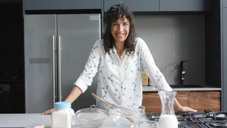 Portrait-of-happy-biracial-woman-baking-in-kitchen,-slow-motion