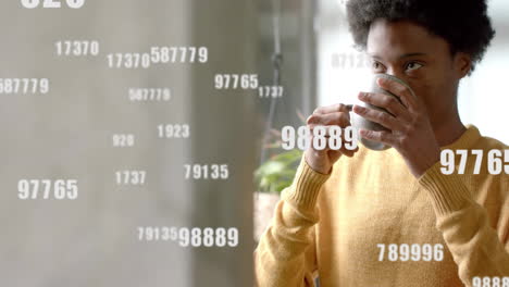 Animation-of-numbers-and-data-processing-over-african-american-man-with-tea-in-office
