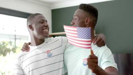 Amigos-Afroamericanos-Celebran-En-Casa,-Usando-Insignias-De-Voto-Con-Banderas-Americanas