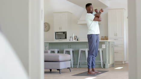 Fokussierter-Afroamerikanischer-Mann,-Der-Sich-Im-Sonnigen-Wohnzimmer-Streckt,-Zeitlupe