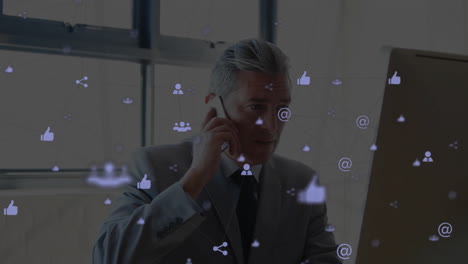 Animation-of-network-of-connections-with-icons-over-caucasian-businessman-using-computer
