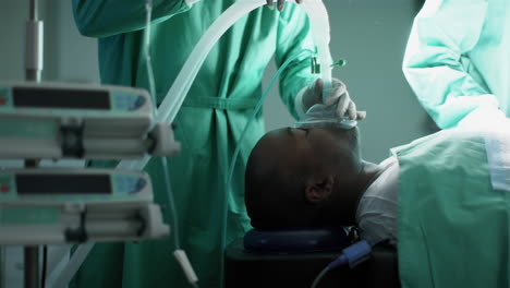 Surgeon-using-anaesthetic-mask-on-african-american-male-patient-in-operating-theatre,-slow-motion