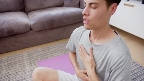 Biracial-Mann,-Der-Yoga-Meditation-Praktiziert,-Sitzt-Auf-Dem-Wohnzimmerboden,-Kopierraum,-Zeitlupe