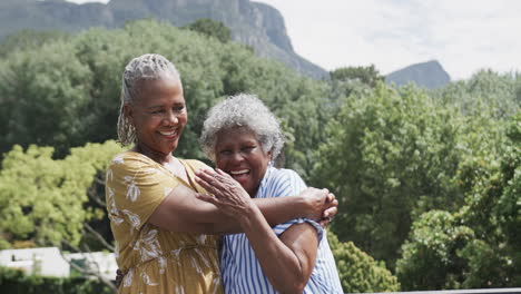 Portrait-of-happy-senior-african-american-female-friends-embracing-on-balcony,-slow-motion
