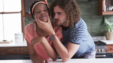 Diverse-couple:-a-young-African-American-woman-and-Caucasian-man-make-funny-faces-in-a-home-kitchen
