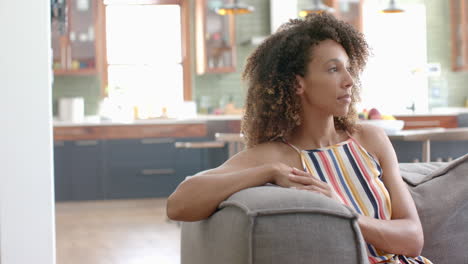 Biracial-woman-relaxes-on-a-sofa-at-home-with-copy-space