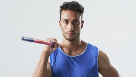 Young-biracial-athlete-man-holding-a-javelin-in-a-studio-setting-on-a-white-background