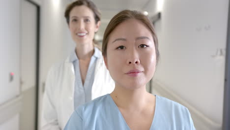 Portrait-of-happy-diverse-female-doctors-standing-in-hospital-corridor,-selective-focus,-slow-motion