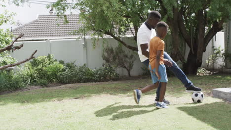 African-American-father-and-son-play-soccer-outdoors