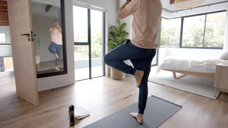 Senior-biracial-man-practicing-yoga-meditation-at-home