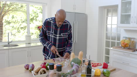 Senior-african-american-man-cutting-vegetables-in-kitchen,-copy-space,-slow-motion