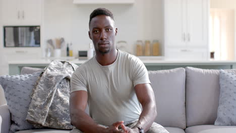 Besorgter-Afroamerikanischer-Soldat,-Der-Auf-Der-Couch-Im-Sonnigen-Wohnzimmer-Sitzt,-Zeitlupe