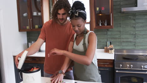Diverse-couple,-a-young-Caucasian-man-and-an-African-American-woman,-composting-food-waste-together-