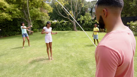 Happy-african-american-parents,-son-and-daughter-skipping-in-sunny-garden,-slow-motion