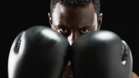 Focused-African-American-boxer-ready-to-fight-on-black-background