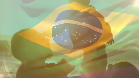 Animation-of-brazilian-flag-over-happy-caucasian-parents-and-child-on-sunny-beach