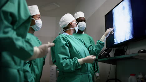 Diverse-surgeons-discussing-with-x-ray-scans-in-operating-theatre-at-hospital,-slow-motion