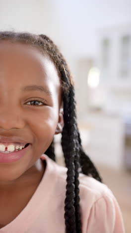 Vertical-video-of-portrait-of-happy-african-american-girl-at-home,-slow-motion