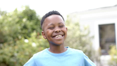 Porträt-Eines-Glücklichen-Afroamerikanischen-Jungen,-Der-Im-Sonnigen-Garten-Lacht,-Zeitlupe