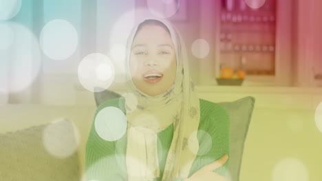 Animation-of-light-spots-over-biracial-woman-in-hijab-smiling