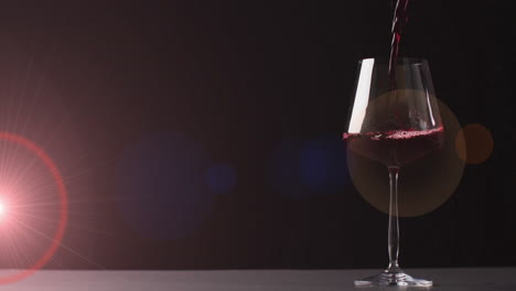 Composite-of-red-wine-being-poured-into-glass-over-dark-red-background