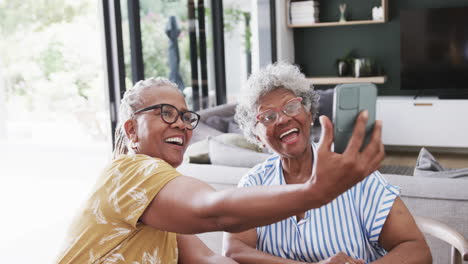 Glückliche-ältere-Afroamerikanische-Freundinnen,-Die-Selfies-Mit-Dem-Telefon-Im-Esszimmer-Machen,-Zeitlupe