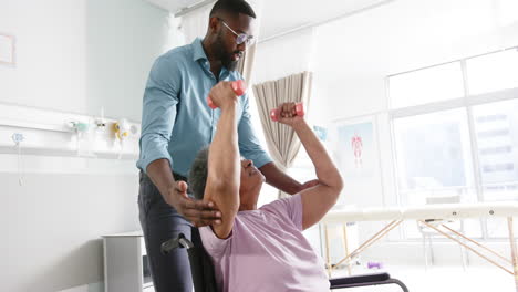 African-american-woman-exercising-with-weights-and-male-doctor-advising-in-hospital,-slow-motion