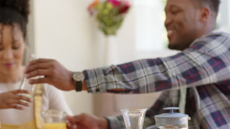 Happy-african-american-parents-and-daughter-having-breakfast-at-home,-slow-motion