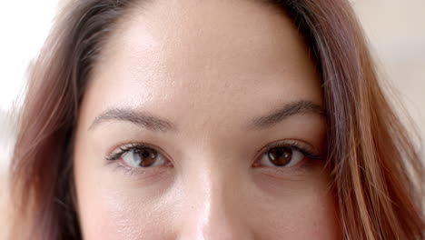 Portrait-close-up-of-eyes-of-happy-biracial-woman-smiling-at-home,-copy-space,-slow-motion