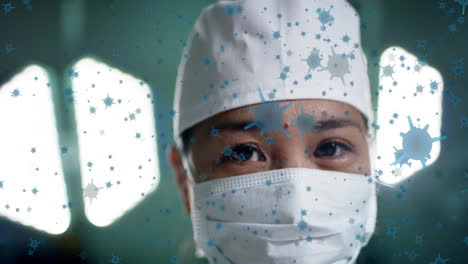 Animation-of-floating-viruses-over-asian-female-surgeon-waring-cap-and-mask-in-hospital