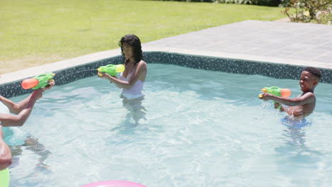 Happy-african-american-parents-and-daughter-playing-with-water-pistols-in-sunny-pool,-slow-motion