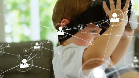 Animation-of-network-of-connections-with-icons-over-caucasian-boy-using-vr-headset