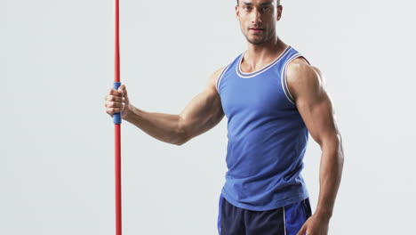 Muscular-athlete-man-holds-a-javelin-at-the-gym-on-a-white-background