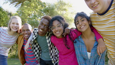 Portrait-of-happy-diverse-group-of-teenage-friends-embracing-in-sunny-park,-slow-motion