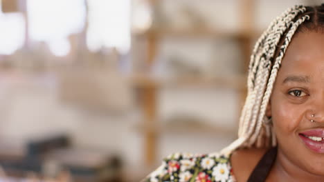 Half-face-of-happy-african-american-woman-with-braids-smiling-in-pottery-studio,-slow-motion