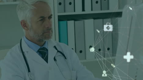 Animation-of-network-of-medical-icons-over-senior-caucasian-male-doctor-using-computer