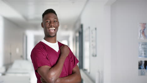 Portrait-of-happy-african-american-male-doctor-wearing-scrubs-in-hospital,-copy-space,-slow-motion